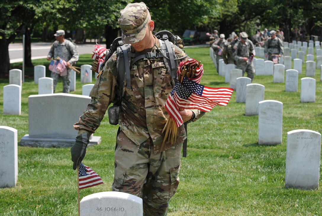 Soldiers place American flags in front of headstones during "Flags In" at Arlington National Cemetery in Arlington, Va., May 26, 2016. DoD photo by Marvin D. Lynchard