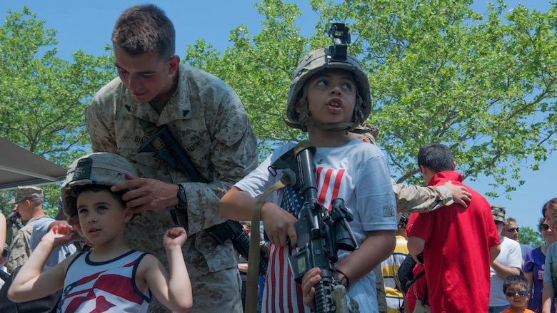 Cpl. Joseph Binari, a rifleman with 3rd Battalion, 6th Marine Regiment, helps a local child try on a Marine helmet during Military Day as part of Fleet Week at Eisenhower Park in East Meadow, New York, May 28, 2016. The Marines and sailors are visiting to interact with the public, demonstrate capabilities and teach the people of New York about America’s sea services.