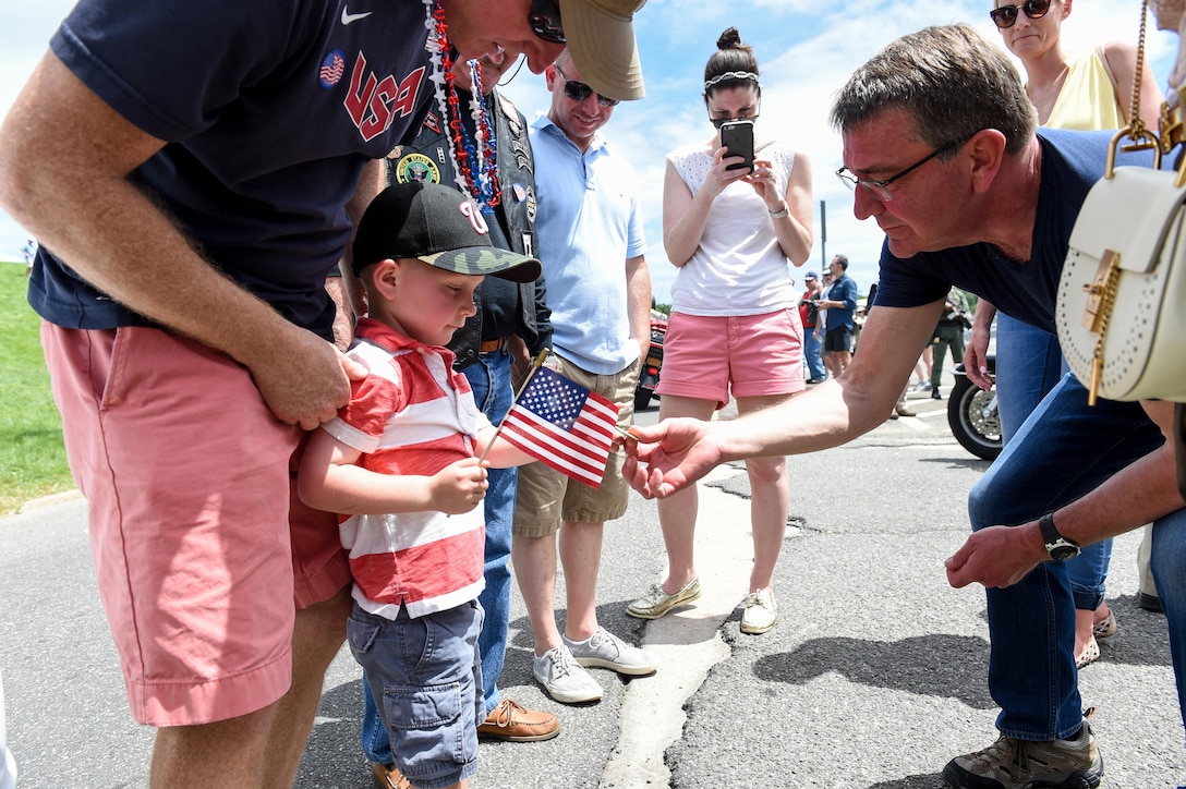 Defense Secretary Ash Carter gives a coin to a little boy attending the Rolling Thunder motorcycle ride at the Pentagon's north parking lot, May 29, 2016. The annual ride aims to raise awareness for prisoners of war and U.S. service members missing in action. DoD photo by Army Sgt. 1st Class Clydell Kinchen