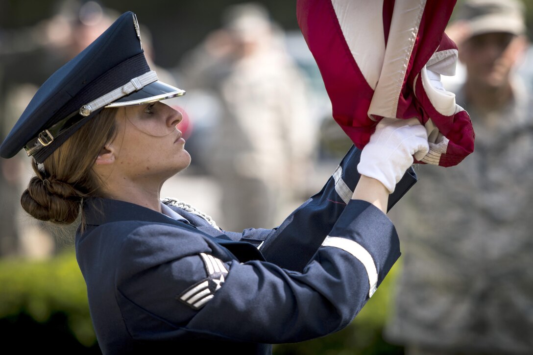 Air Force Senior Airman Tiffany Fogel reaches to secure an American flag as it is lowered during a retreat ceremony to commemorate Memorial Day at Joint Base Andrews, Md., May 26, 2016. Fogel is an administrative assistant and resource advisor assigned to the 99th Airlift Squadron. Air Force photo by Senior Master Sgt. Kevin Wallace