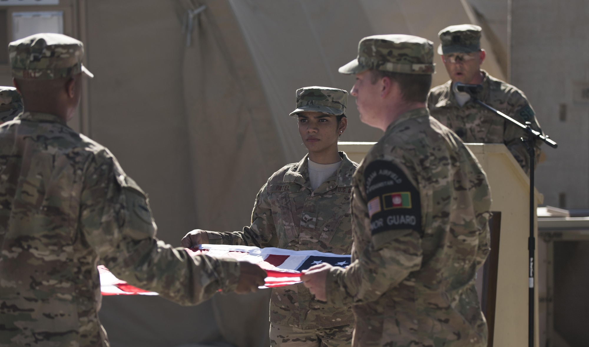 Capt. Benjamin Swope, 455th Expeditionary Security Forces Squadron, reads the names of fallen servicemembers as the base Honor Guard team folds the flag at Bagram Airfield, Afghanistan, May 30, 2016. The Company Grade Officer Council hosted the remembrance ceremony to honor those who gave all in service to our country. (U.S. Air Force photo by Tech. Sgt. Tyrona Lawson)