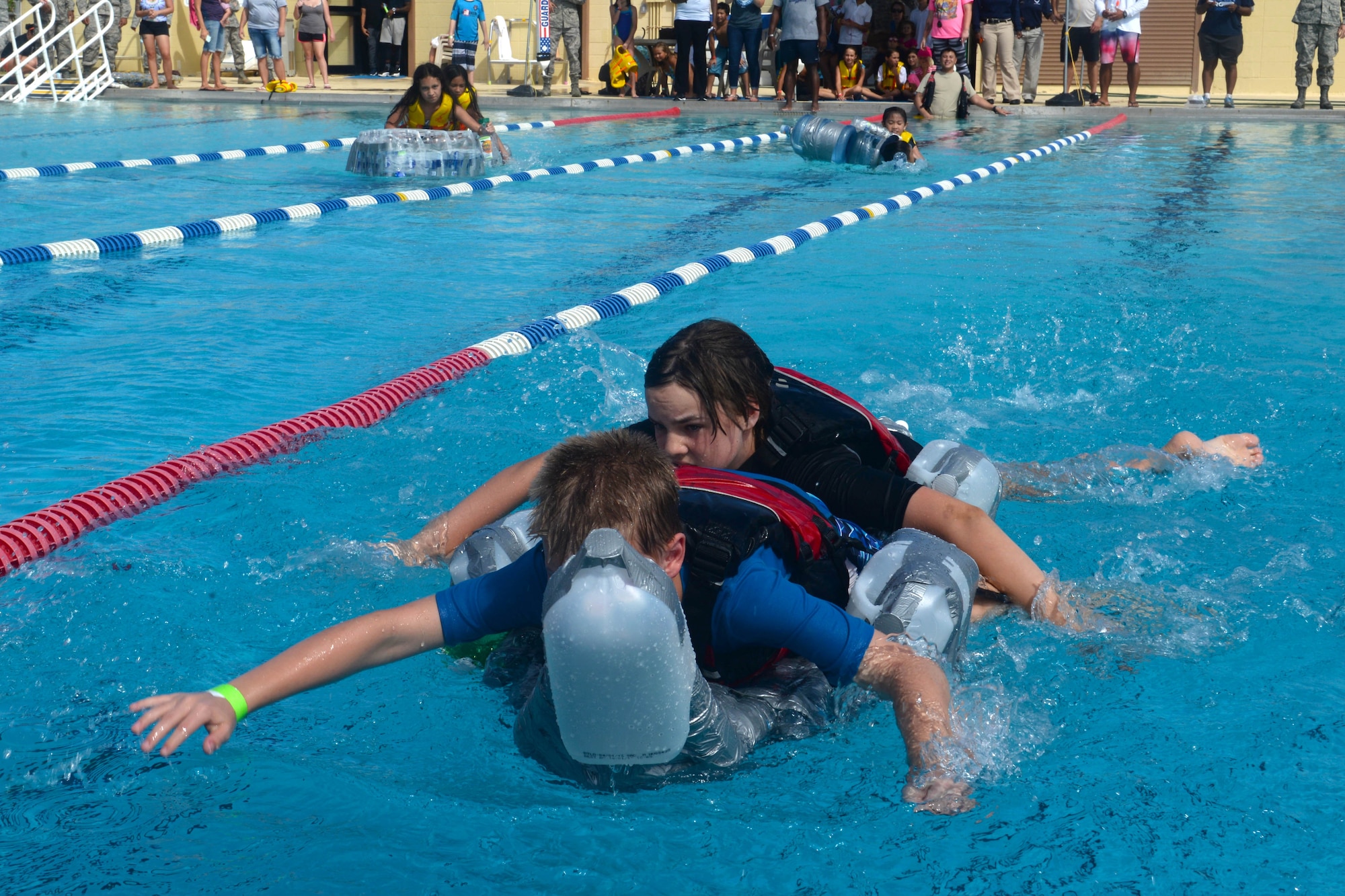 A team of children race a homemade boat during the Boat Blitz May 25, 2016, at Andersen Air Force Base, Guam. Teams of two raced to one end of the base pool and back while attempting to stay on their boat for as long as possible. (U.S. Air Force photo by Airman 1st Class Alexa Ann Henderson)