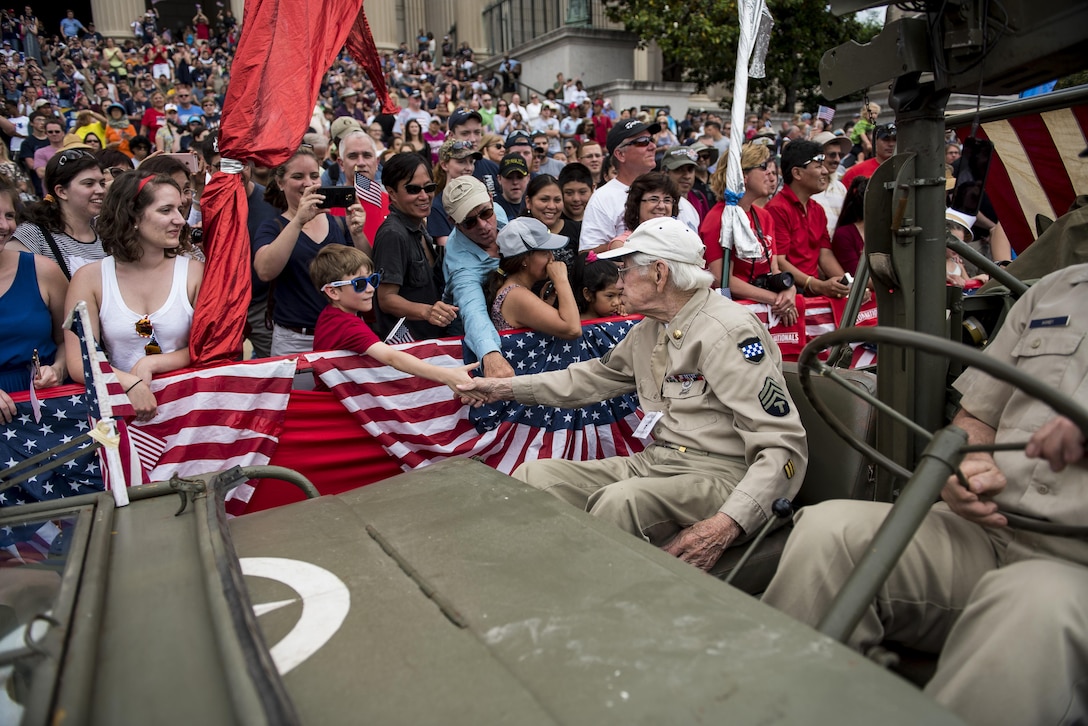 A veteran representing the 99th Infantry Division shakes hands with the crowd along Constitution Avenue in the 2016 National Memorial Day Parade in Washington, D.C., May 30. (U.S. Army photo by Master Sgt. Michel Sauret)