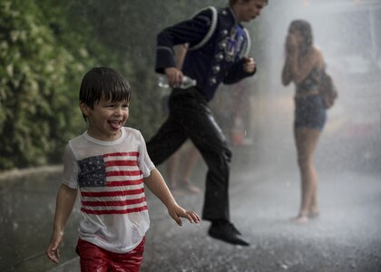 A group of children and teenagers play under the water spray from a fire truck at the end of the route of the 2016 National Memorial Day Parade in Washington, D.C., May 30. U.S. Army Reserve Soldiers marched in the parade, represented by the 200th Military Police Command, from Fort Meade, Maryland; the 55th Sustainment Brigade, from Fort Belvoir, Virginia; and the Military Intelligence Readiness Command, from Fort Belvoir. (U.S. Army photo by Master Sgt. Michel Sauret)