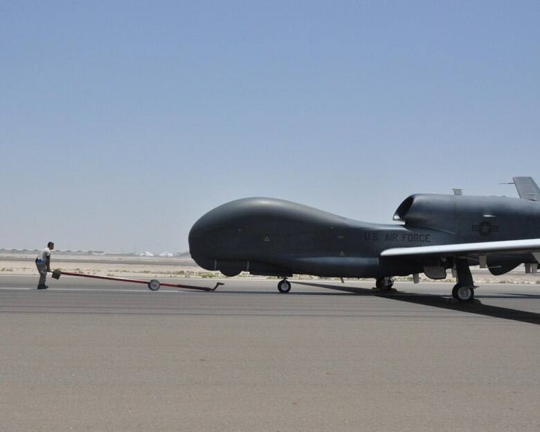 Staff Sgt. Phillip, 380th Expeditionary Aircraft Maintenance Squadron Global Hawk technician, moves to attach a tow bar to an RQ-4 Global Hawk, May 16, to guide it back into an aircraft hangar after flight. Maintainers are responsible for inspecting and replacing components, cleaning, touching up paint, clearing any fault alerts, and towing the aircraft to and from the flight line. (U.S. Air Force photo by Staff Sgt. Samantha Mathison)
