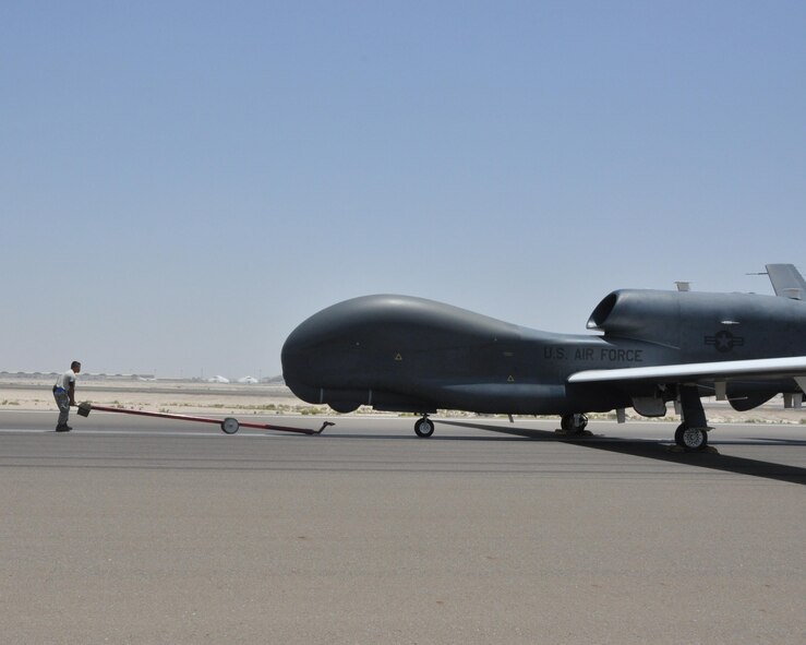 Staff Sgt. Phillip, 380th Expeditionary Aircraft Maintenance Squadron Global Hawk technician, moves to attach a tow bar to an RQ-4 Global Hawk, May 16, to guide it back into an aircraft hangar after flight. Maintainers are responsible for inspecting and replacing components, cleaning, touching up paint, clearing any fault alerts, and towing the aircraft to and from the flight line. (U.S. Air Force photo by Staff Sgt. Samantha Mathison)