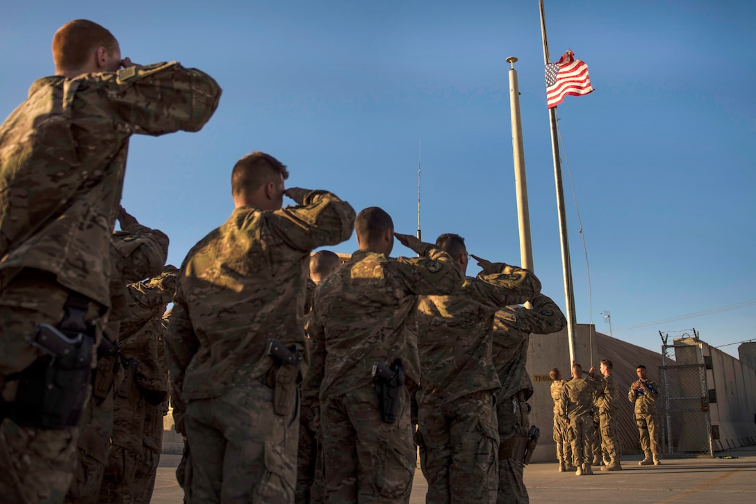 Airmen salute the lowering of a flag during a flag retirement ceremony at Bagram Airfield, Afghanistan, May 28, 2016. The airmen are assigned to the 455th Expeditionary Civil Engineer Squadron. The unit raised a new flag for Memorial Day events. Air Force photo by Senior Airman Justyn M. Freeman