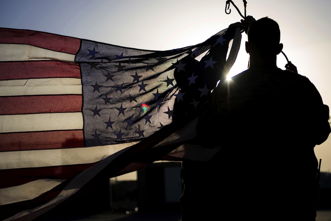 Airmen raise a new flag during a flag retirement ceremony at Bagram Airfield, Afghanistan, May 28, 2016. Air Force photo by Senior Airman Justyn M. Freeman