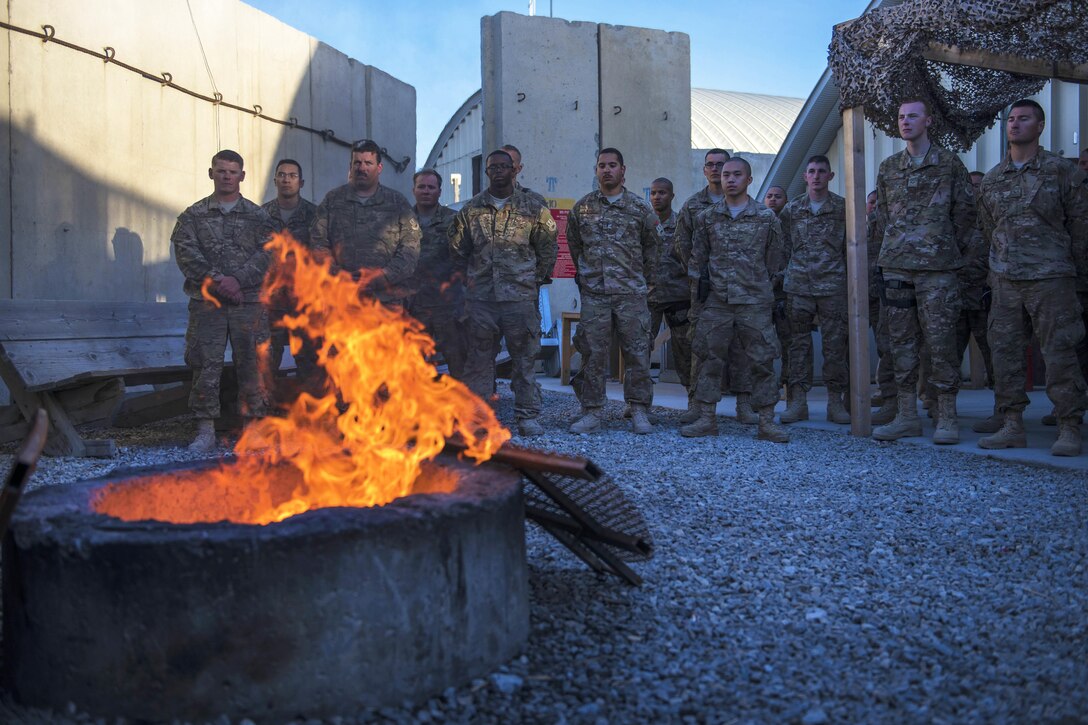 Airmen show respect while an old flag is burned during a flag retirement ceremony at Bagram Airfield, Afghanistan, May 28, 2016. Air Force photo by Senior Airman Justyn M. Freeman