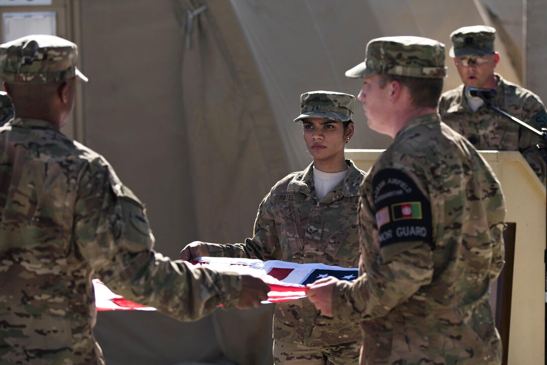 Air Force Capt. Benjamin Swope, right, reads the names of fallen service members while the honor guard folds the flag during a Memorial Day remembrance ceremony at Bagram Airfield, Afghanistan, May 30, 2016. Air Force photo by Tech. Sgt. Tyrona Lawson