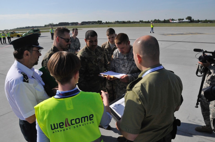 Polish forces, airport security, and U.S. Army Soldiers discuss procedures during the delivery of 20 Oklahoma National Guard Soldiers and equipment at the Gdańsk Lech Wałęsa Airport, May 25.
