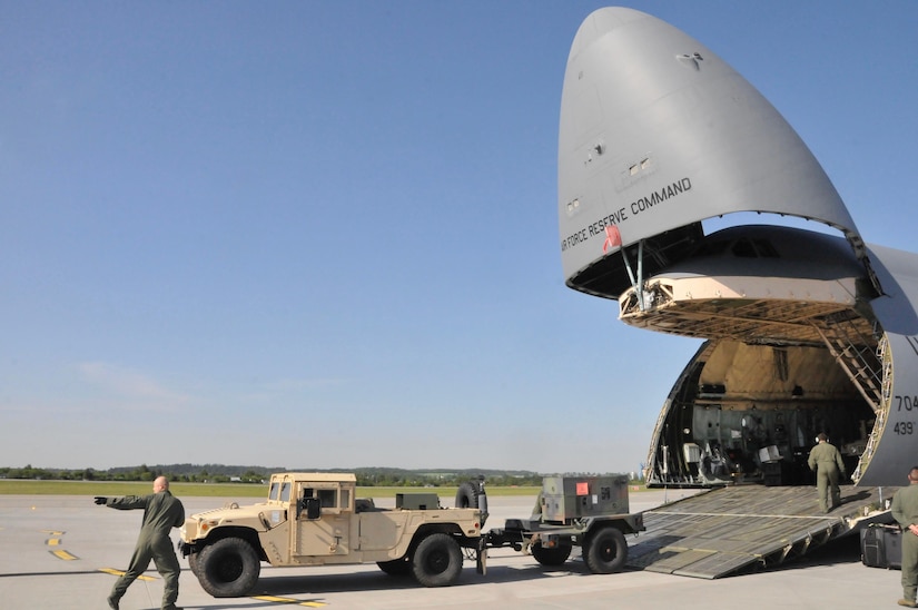 A 439th Airlift Wing Flight Crew member directs the unloading of a Humvee from a C-5 Galaxy at the Gdańsk Lech Wałęsa Airport in Poland, May 25.