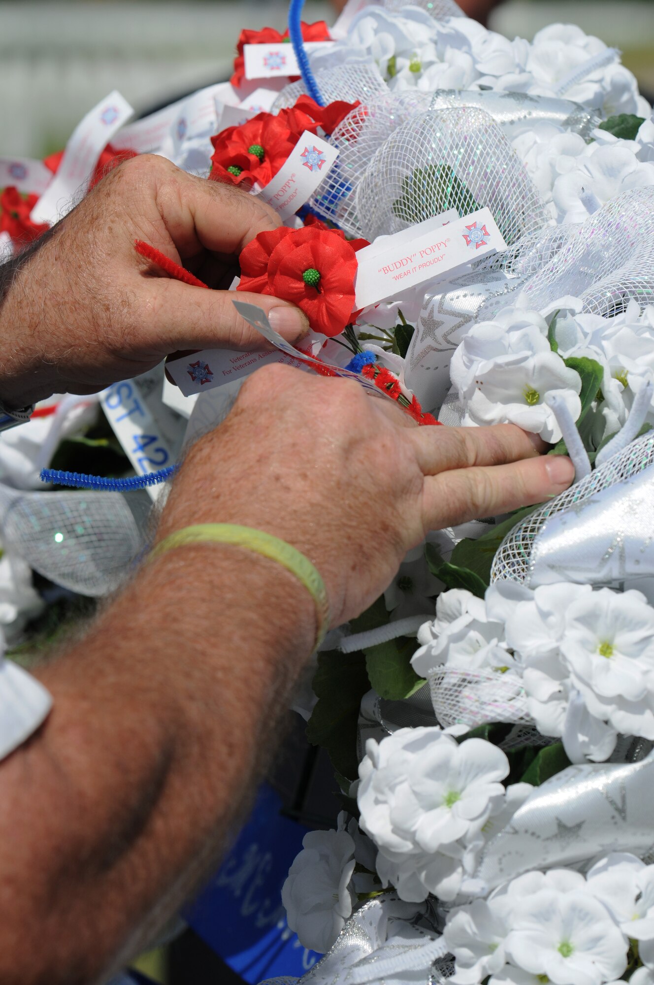 A “Buddy” Poppy is placed on a wreath during the Memorial Day Ceremony May 30, 2016, Biloxi, Miss. Local veterans, family members and Keesler Air Force Base personnel attended the event at the Biloxi National Cemetery to honor and remember the lives of fallen heroes of the U.S. military. (U.S. Air Force photo by Kemberly Groue)