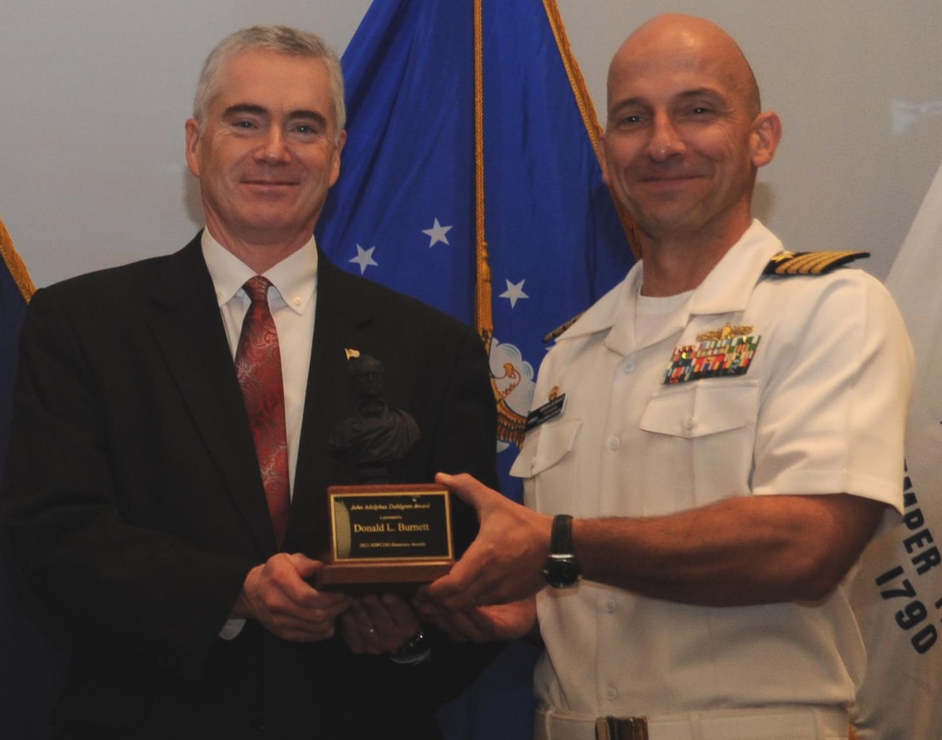 DAHLGREN, Va. - Naval Surface Warfare Center Dahlgren Division (NSWCDD) Commanding Officer Capt. Brian Durant presents Dohn Burnett with the John Adolphus Dahlgren Award for his years of exceptional technical and organizational leadership of NSWCDD at the command's Annual Honor Awards ceremony on May 18, 2016. "Mr. Burnett achieved numerous technical milestones throughout his exemplary career, including the integration and installation of the Aegis Baseline 9 combat system, basis cyber capability integration, establishment of the Fast Frigate Program, and the foundation for integration of railgun and laser systems into surface combatants," according to the  citation.