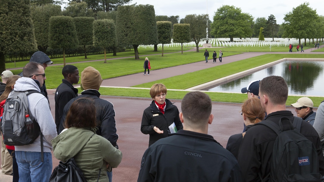 A French tour guide talks to Marines from Headquarters and Service Battalion, Headquarters Marine Corps, Henderson Hall and Marine Barracks Washington, D.C, at Normandy American Cemetery and Memorial in Coleville sur Mer, France, May 25, 2016. The cemetery overlooks Omaha Beach and is the final resting place of more than 9,000 American service members and honors more than 1,500 American service members who are missing in action. 