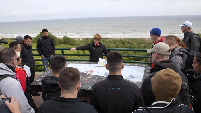 Marines from Headquarters and Service Battalion, Headquarters Marine Corps, Henderson Hall and Marine Barracks Washington, D.C. listen as a French guide at the Normandy American Cemetery and Memorial explains how American troops landed at Omaha Beach, June 6, 1944, during World War Two in Coleville sur Mer, France, May 25, 2016. The cemetery overlooks Omaha Beach and is the final resting place of more than 9,000 American service members and honors more than 1,500 American service members who are missing in action. 