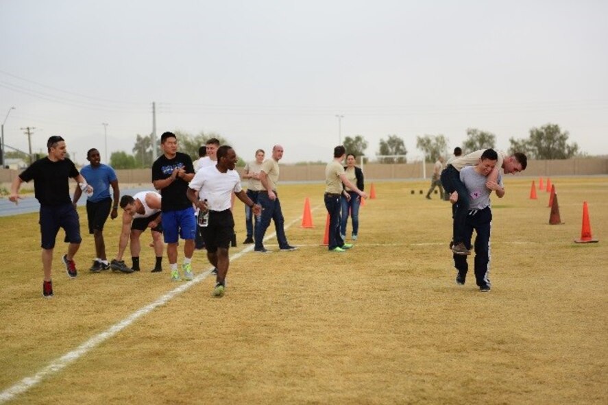A Development Training Flight trainee carries a fellow trainee while other DTF members cheer them on during the 944th Fighter Wing Physical Training Challenge, April 30, 2016. A total of nine four-person teams competed during this month's challenge.  DTF teams took second and third place with the 944th Security Forces Squadron taking first.