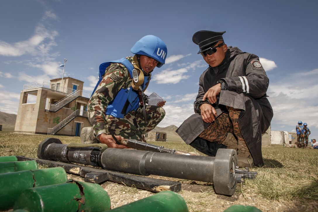 A service member with the Nepalese Army inspects simulated weapons and explosives gathered
during training with a role player during the cordon and search training lane at Khaan Quest 2016, Five Hills Training Area, Mongolia, May 30, 2016. The cordon and search training lane teaches participants how to block off and search an area, and is one of eleven training lanes set up at Khaan Quest for the multinational platoons to learn and improve skills necessary to be successful in peacekeeping operations. Khaan Quest is an annual, multinational peacekeeping operations exercise hosted by the Mongolian Armed Forces, co-sponsored by U.S. Pacific Command, and supported by U.S. Army Pacific and U.S. Marine Corps Forces, Pacific. Khaan Quest, in its 14th iteration, is the capstone exercise for this year’s Global Peace Operations Initiative program. The exercise focuses on training activities to enhance international interoperability, develop peacekeeping capabilities, build to mil-to-mil relationships, and enhance military readiness.
