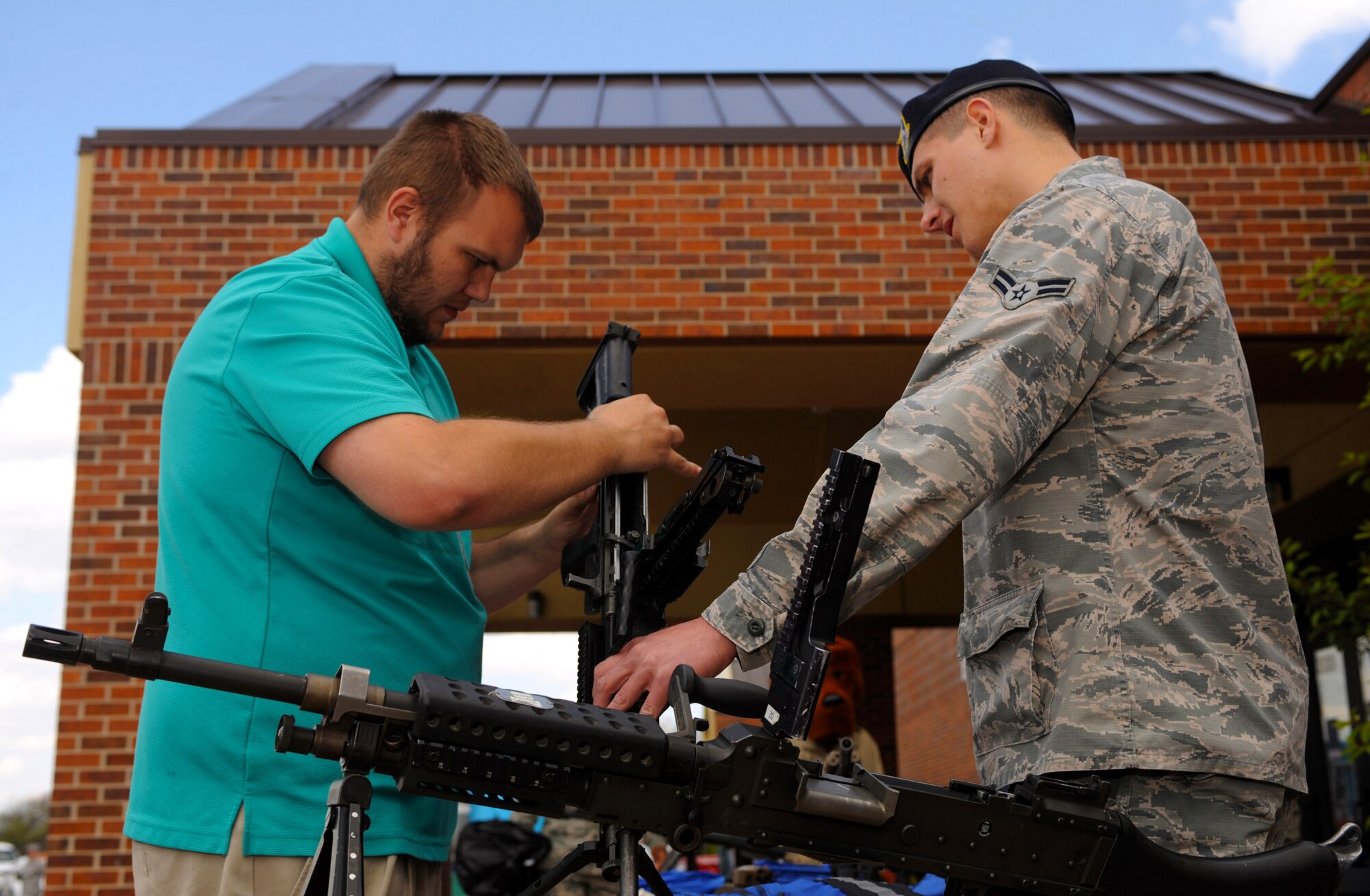 Kody Greeno, 28th Medical Group contractor, and Airman 1st Class John Stumpf, 28th Security Forces Squadron response force member, look at a weapon on display at the base Exchange as part of National Police Week at Ellsworth Air Force Base, S.D., May 17, 2016. Security personnel qualify with the M-4 rifle and M-9 handgun, while also undergoing a 65-day training course at Lackland Air Force Base, Texas, which teaches basic military police functions such as missile security, convoy actions and law enforcement. (U.S. Air Force photo by Airman 1st Class Denise M. Nevins/Released)