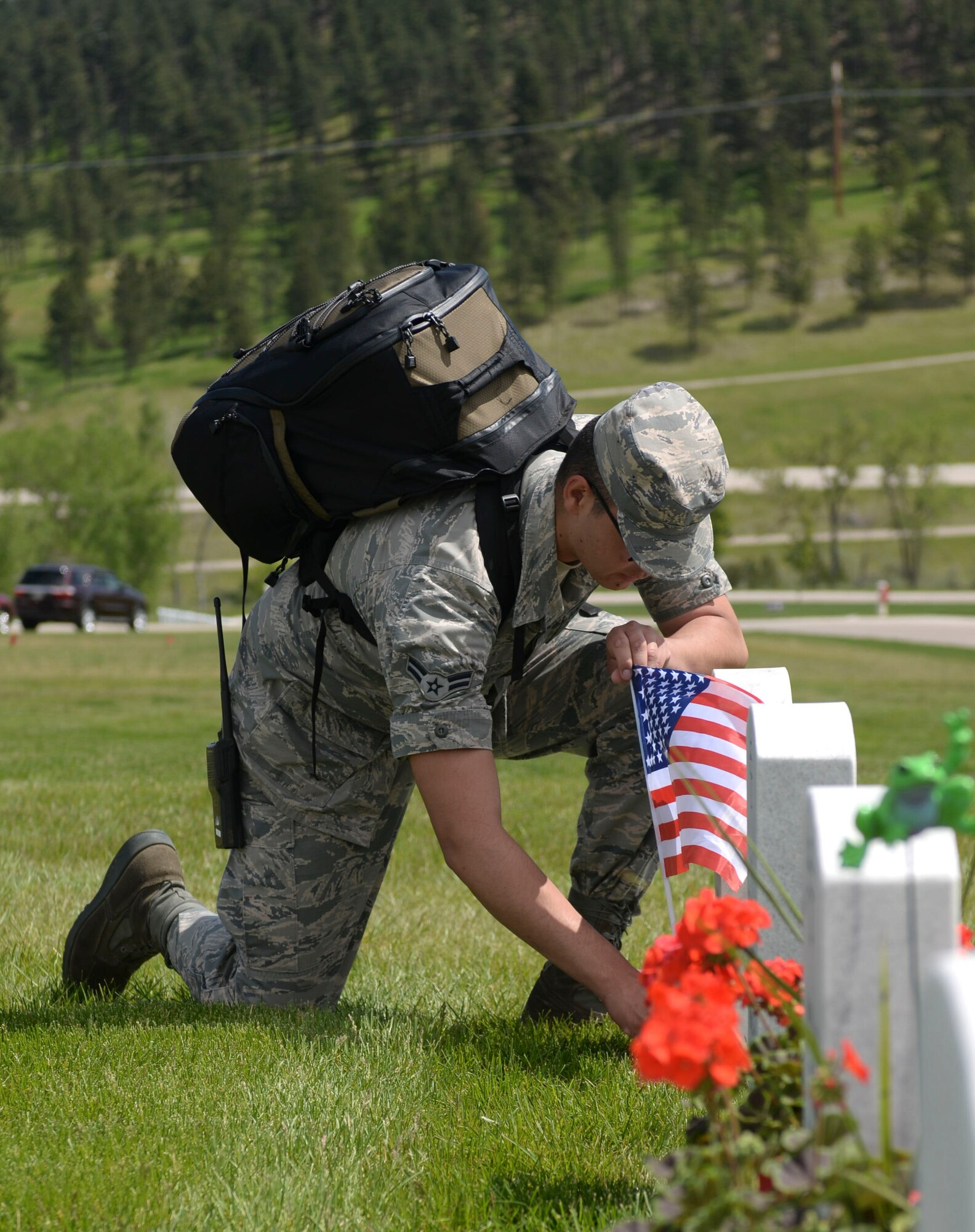 Airman 1st Class Ignacio Luna, 28th Aircraft Maintenance Squadron weapons load crewmember, places a flag in front of a tombstone for a deceased military member at the Black Hills National Cemetery in Sturgis, S.D., May 28, 2016. Approximately 608 burials are conducted each year in the cemetery. (U.S. Air Force photo by Airman 1st Class Sadie Colbert/Released)
