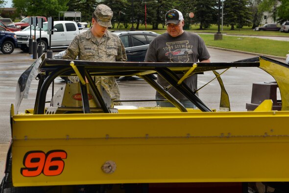 Eric Folstad, driver of the 96F racecar, talks with Staff Sgt. Joshua Nauman, NCO in charge of transmission systems assigned to the 5th Communications Squadron, about what size of an engine goes into a racecar at Minot Air Force Base, N.D., May 25, 2016. Folstad displayed his car at the Base Exchange for a giveaway and to inform Airmen about Military Appreciation Day on May 30. (U.S. Air Force photo/Airman 1st Class Jessica Weissman)
