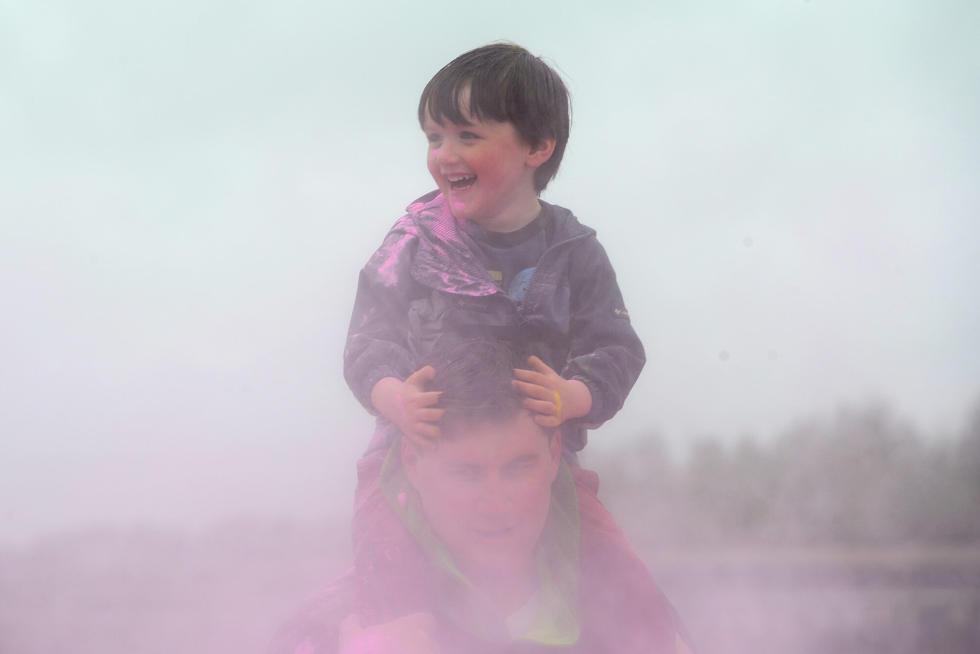 A child smiles over clouds of pink during the America’s Armed Forces Color Run at Joint Base Elmendorf-Richardson, Alaska, May 21, 2016. The Alaska Military Youth Academy, JBER Life, USO, and volunteers provided water, food, photo opportunities, and dye at multiple stations along the run. (U.S. Air Force photo by Airman 1st Class Christopher R. Morales)
