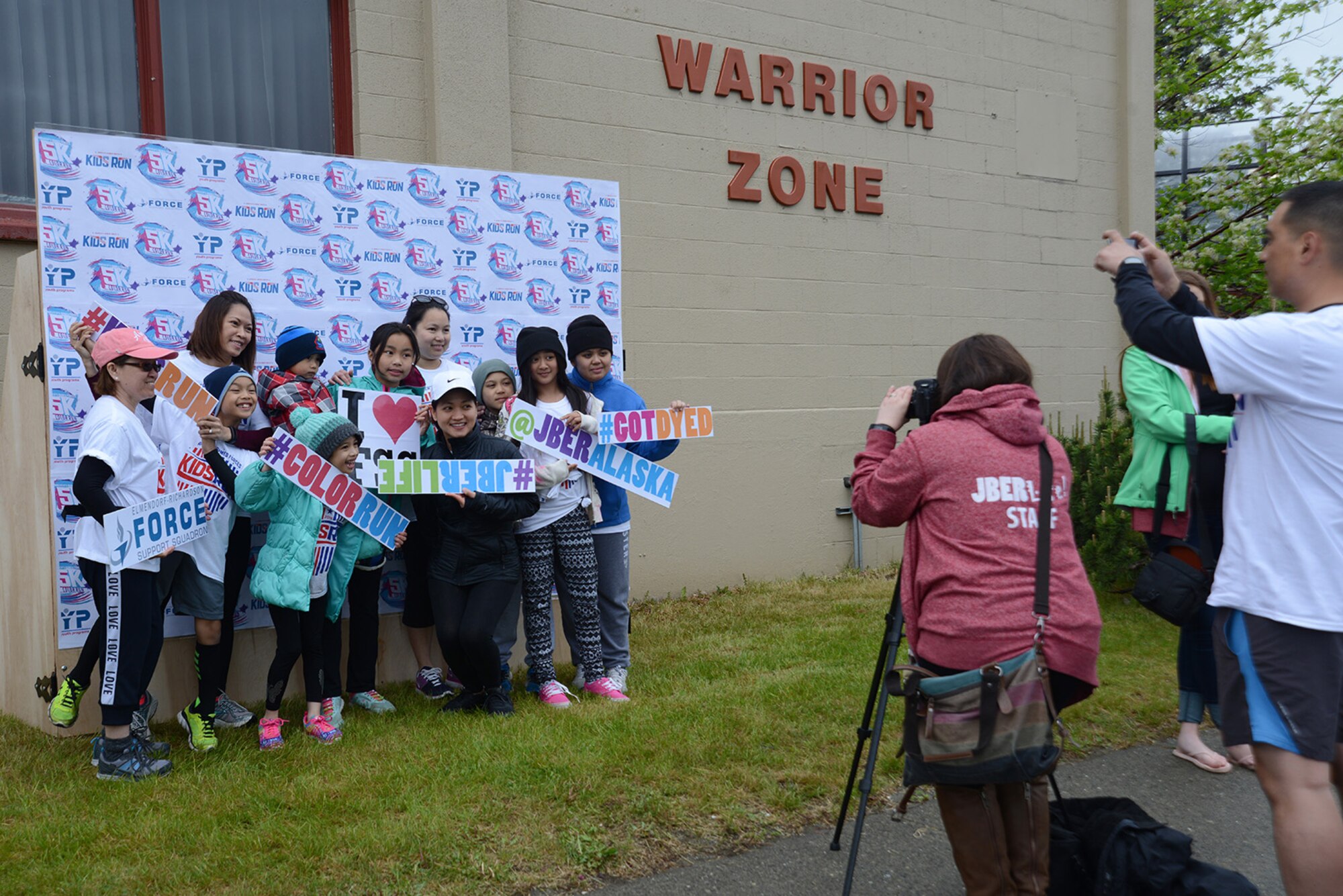 Joint Base Elmendorf-Richardson Life personnel take pictures of families before and after the America’s Armed Forces Color Run at JBER, Alaska, May 21, 2016. The Alaska Military Youth Academy, JBER Life, USO, and volunteers provided water, food, photo opportunities, and dye at multiple stations along the run. (U.S. Air Force photo by Airman 1st Class Christopher R. Morales)