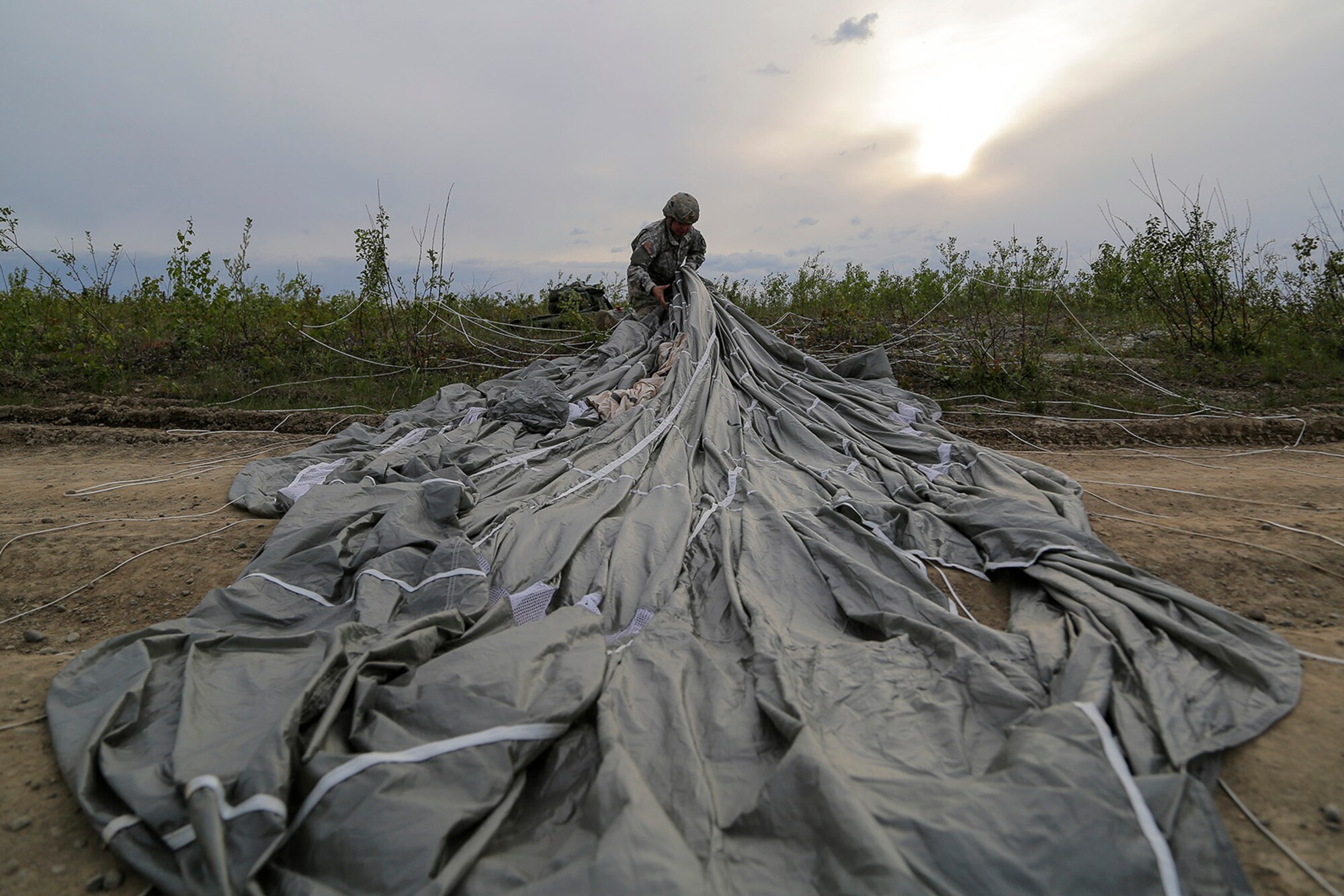 U.S. Army Spc. Donald Shingleton, assigned to the 1st Battalion, 501st Parachute Infantry Regiment, 4th Infantry Brigade Combat Team (Airborne), 25th Infantry Division, recovers his parachute during joint airborne and air transportability training (JAATT) at Joint Base Elmendorf-Richardson, Alaska, May 19, 2016. JAATT familiarizes units with establishing drop zones and airfields, as well as proper communication with aircraft supporting resupply missions. The Soldiers of 4/25 IBCT belong to the only American airborne brigade in the Pacific and are trained to execute airborne maneuvers in extreme cold weather/high altitude environments in support of combat, partnership and disaster relief operations. (U.S. Air Force photo by Alejandro Pena)