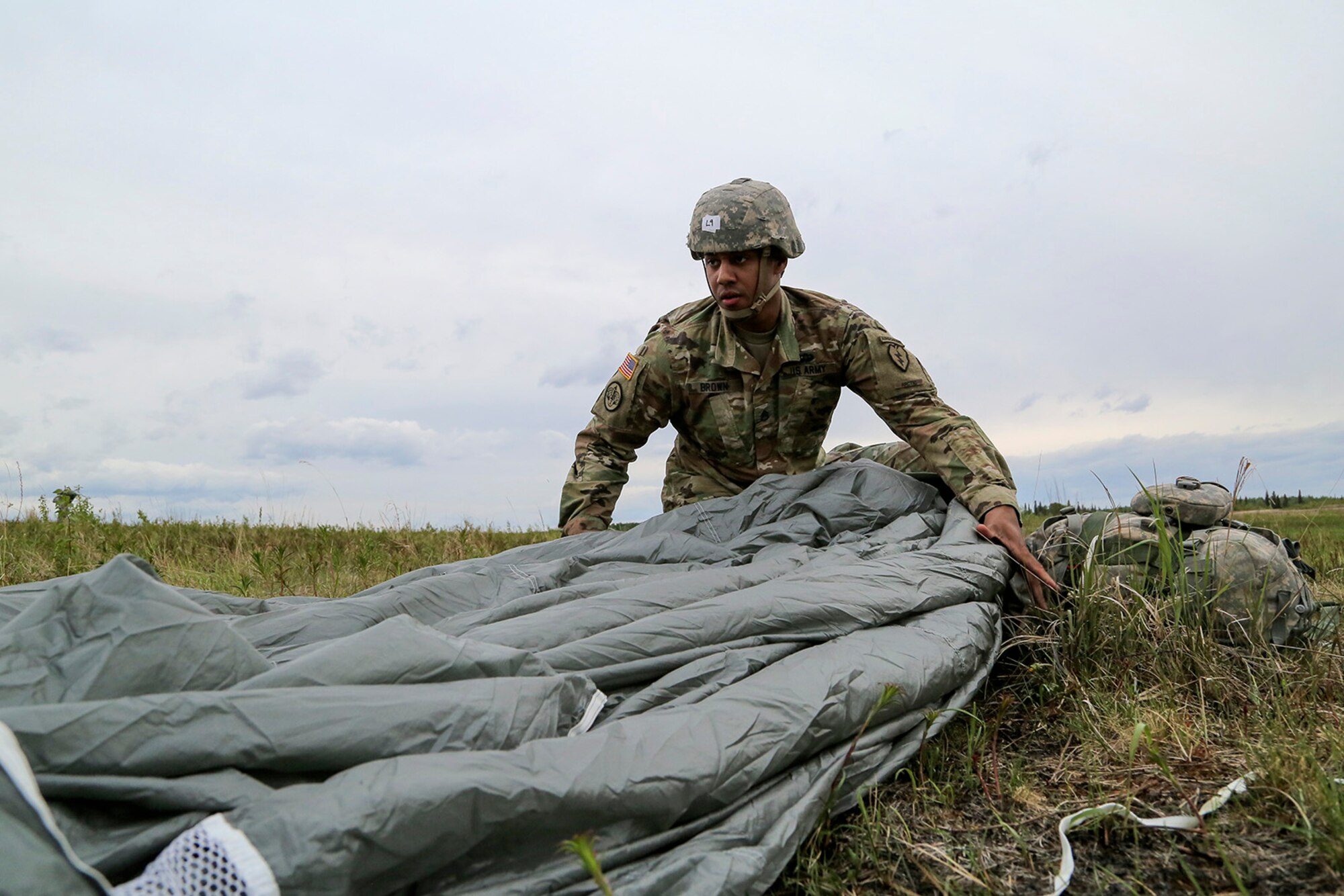 U.S. Army Staff Sgt. Kevin Brown, assigned to the 1st Battalion, 501st Parachute Infantry Regiment, 4th Infantry Brigade Combat Team (Airborne), 25th Infantry Division, recovers his parachute during joint airborne and air transportability training (JAATT) at Joint Base Elmendorf-Richardson, Alaska, May 19, 2016. JAATT familiarizes units with establishing drop zones and airfields, as well as proper communication with aircraft supporting resupply missions. The Soldiers of 4/25 IBCT belong to the only American airborne brigade in the Pacific and are trained to execute airborne maneuvers in extreme cold weather/high altitude environments in support of combat, partnership and disaster relief operations. (U.S. Air Force photo by Alejandro Pena)