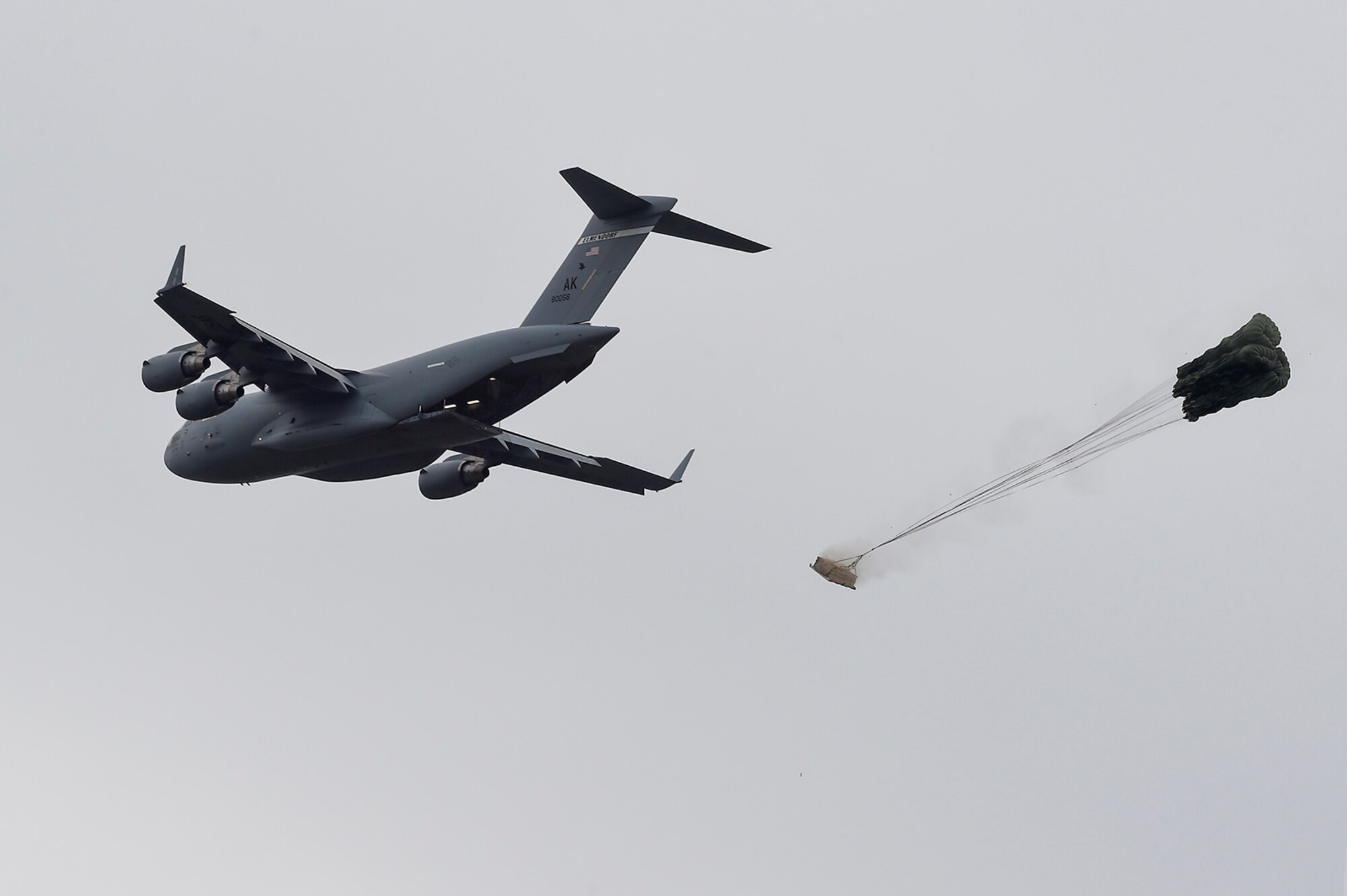 A U.S. Air Force C-17 Globemaster III, assigned to the 517th Airlift Squadron, drops a training resupply bundle during a joint airborne and air transportability training event at Joint Base Elmendorf-Richardson, Alaska, May 19, 2016. JAATT familiarizes units with establishing drop zones and airfields, as well as proper communication with aircraft supporting resupply missions. (U.S. Air Force photo by Alejandro Pena)