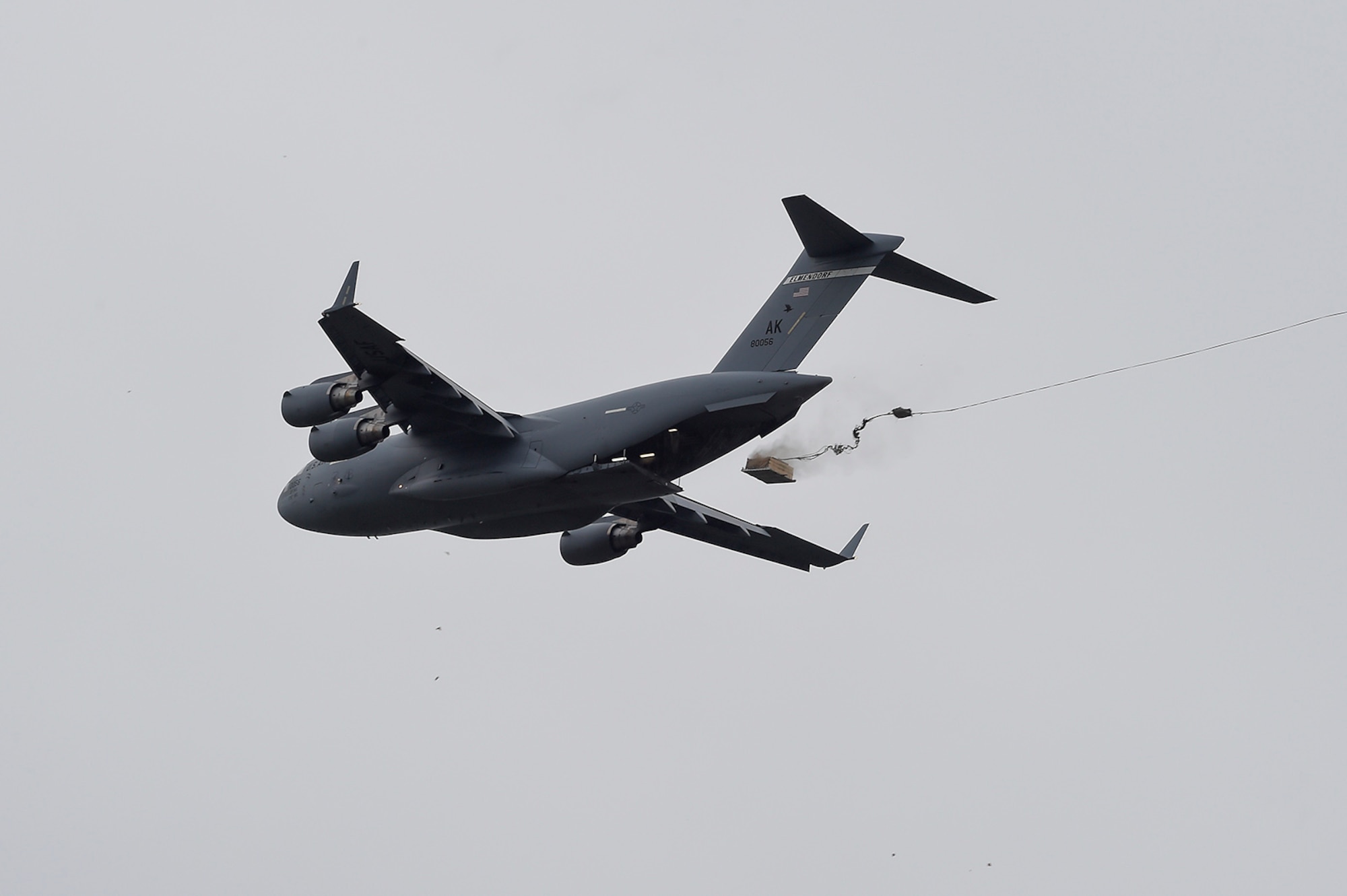 A U.S. Air Force C-17 Globemaster III, assigned to the 517th Airlift Squadron, drops a training resupply bundle during a joint airborne and air transportability training event at Joint Base Elmendorf-Richardson, Alaska, May 19, 2016. JAATT familiarizes units with establishing drop zones and airfields, as well as proper communication with aircraft supporting resupply missions. (U.S. Air Force photo by Alejandro Pena)