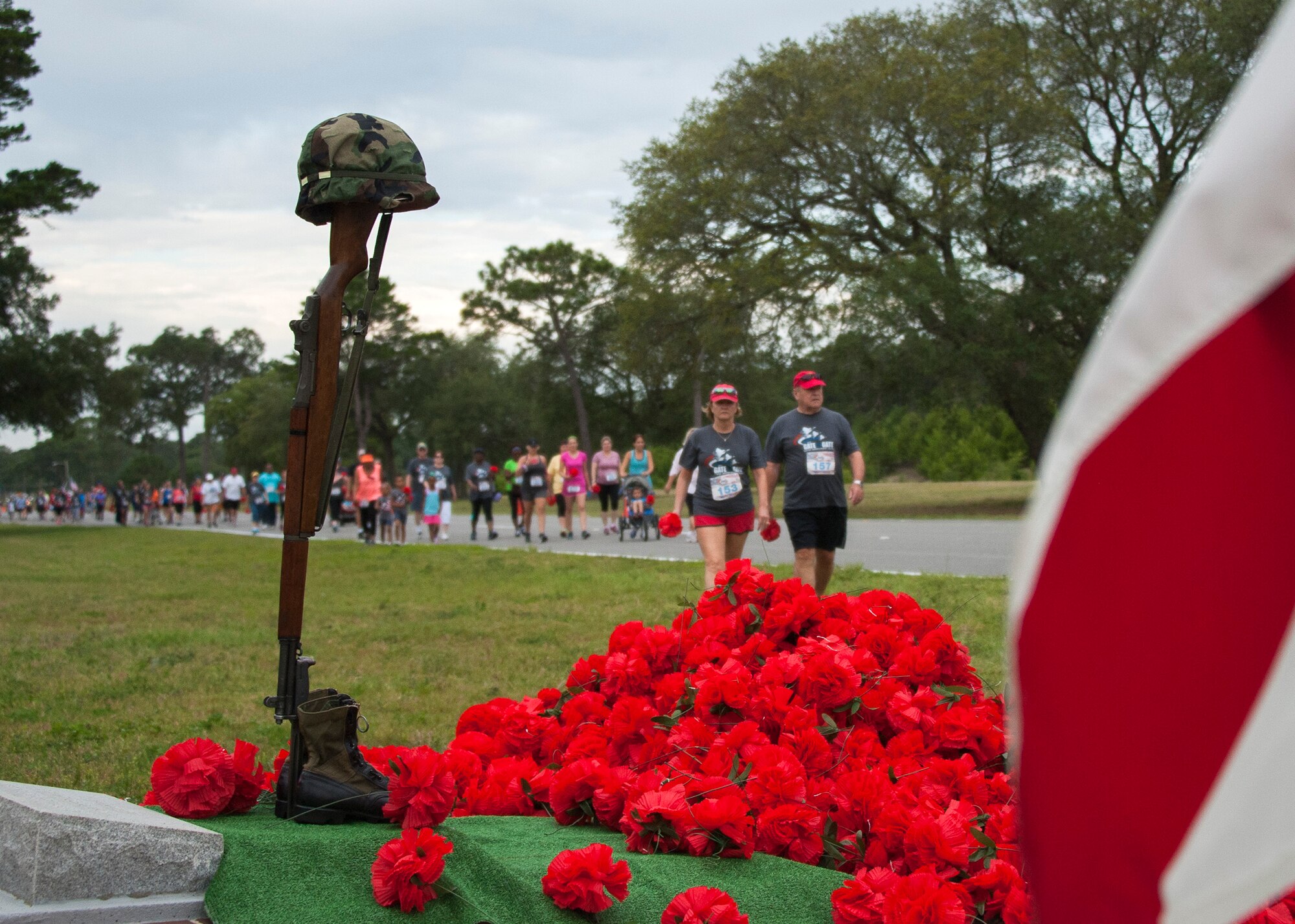Run participants drop red flowers during the 31st annual Gate to Gate Run May 28 at Eglin Air Force Base, Fla. More than 1,050 runners and walkers partook in the Memorial Day Race and paid respects to the country’s fallen with red flowers at the All Wars Memorial as they ran by. (U.S. Air Force photo/Ilka Cole)