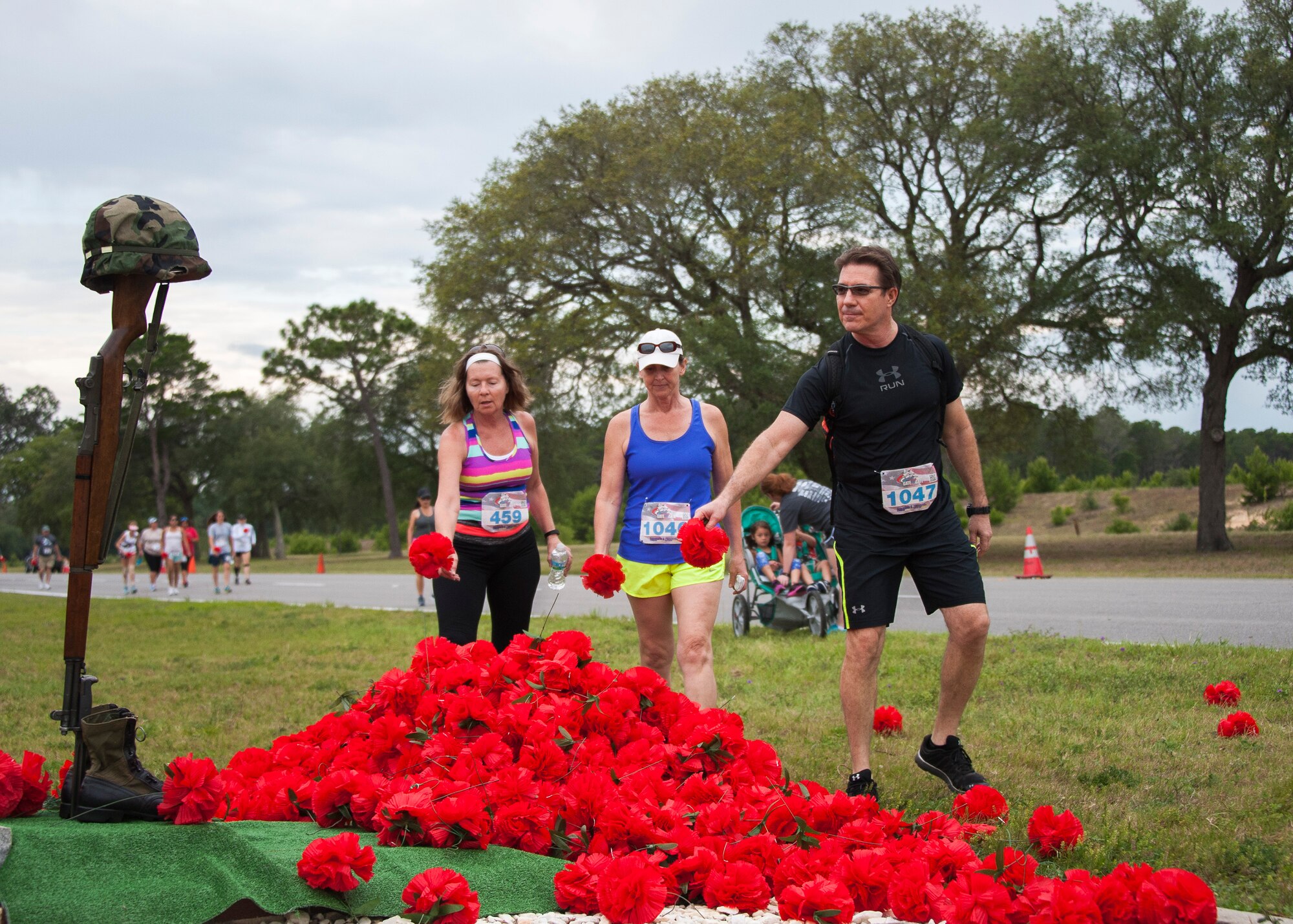 Run participants drop red flowers during the 31st annual Gate to Gate Run May 28 at Eglin Air Force Base, Fla. More than 1,050 runners and walkers partook in the Memorial Day Race and paid respects to the country’s fallen with red flowers at the All Wars Memorial as they ran by. (U.S. Air Force photo/Ilka Cole)