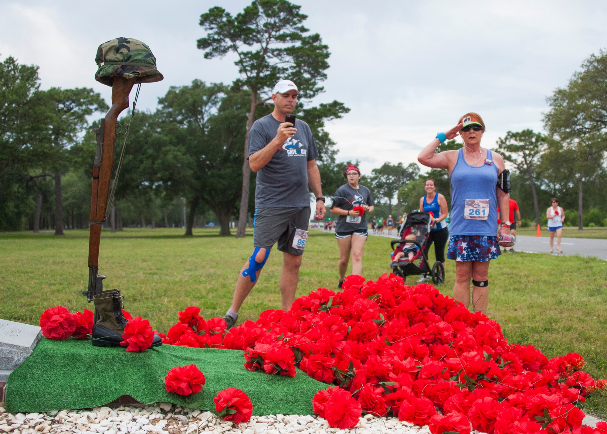 Run participants drop red flowers during the 31st annual Gate to Gate Run May 28 at Eglin Air Force Base, Fla. More than 1050 runners and walkers partook in the Memorial Day Race and paid respects to the country’s fallen with red flowers at the All Wars Memorial as they ran by. (U.S. Air Force photo/Ilka Cole)