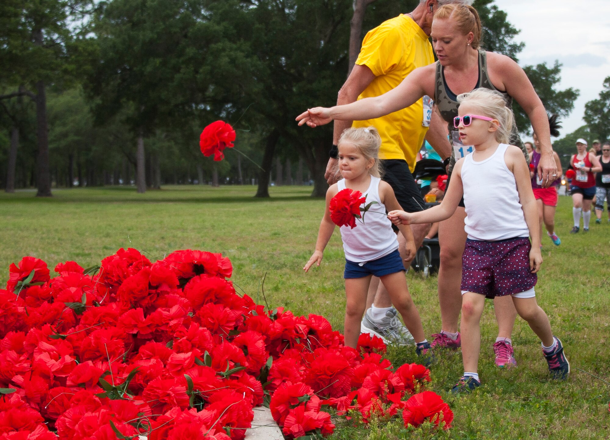 Run participants drop red flowers during the 31st annual Gate to Gate Run May 28 at Eglin Air Force Base, Fla. More than 1,050 runners and walkers partook in the Memorial Day Race and paid respects to the country’s fallen with red flowers at the All Wars Memorial as they ran by. (U.S. Air Force photo/Ilka Cole)