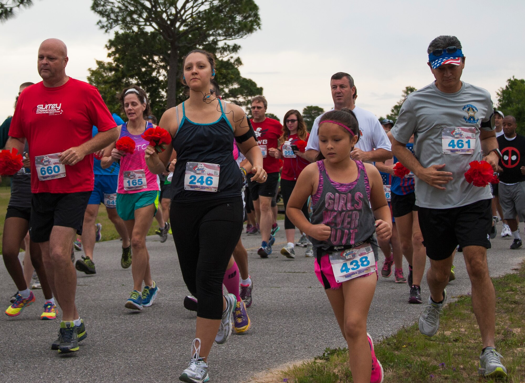 Runners carry red flowers during the 31st annual Gate to Gate Run May 28 at Eglin Air Force Base, Fla. More than 1,050 runners and walkers partook in the Memorial Day Race and paid respects to the country’s fallen with red flowers at the All Wars Memorial as they ran by. (U.S. Air Force photo/Ilka Cole)