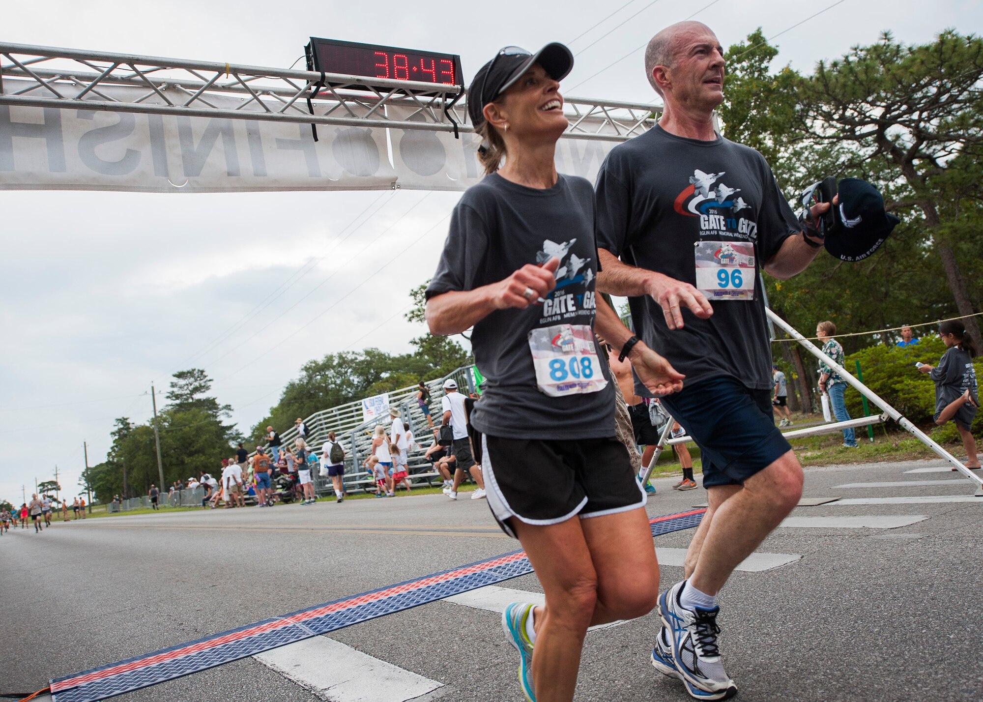 Brig. Gen. Christopher Azzano, 96th Test Wing commander and his wife, Jennifer, cross the finish line together during the 31st annual Gate-to-Gate Run May 28 at Eglin Air Force Base, Fla. More than 1,050 runners and walkers partook in the Memorial Day Race and paid respects to the country’s fallen with red flowers at the All Wars Memorial as they ran by. (U.S. Air Force photo/Ilka Cole)