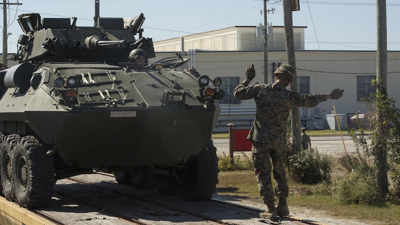 A Marine provides ground guidance for a light armored vehicle onto a railcar during railhead operation training at Camp Lejeune, N.C., Oct. 26, 2016. 2nd Transportation Support Battalion participated in the training to get Marines certified to conduct railhead operations in the future. The Marines are with 2nd TSB. 