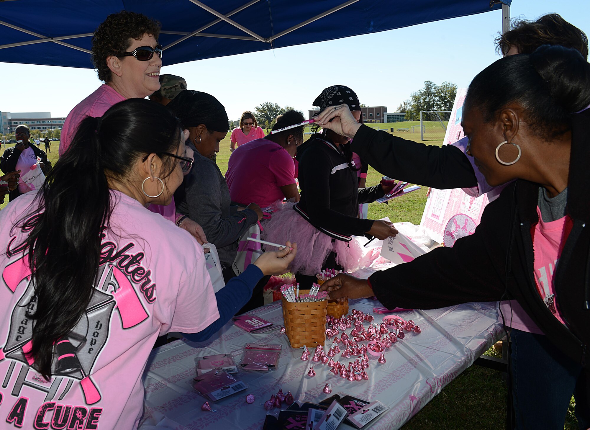 Members of the Joint Base Langley-Eustis, community grab miscellaneous items available during the Breast Cancer Awareness Month walk at JBLE, Va., Oct. 28, 2016. Each year during the month of October, medical professionals and breast cancer awareness organizations work together to educate women on the importance of detecting and preventing breast cancer. (U.S. Air Force photo by Staff Sgt. Teresa J. Cleveland)
