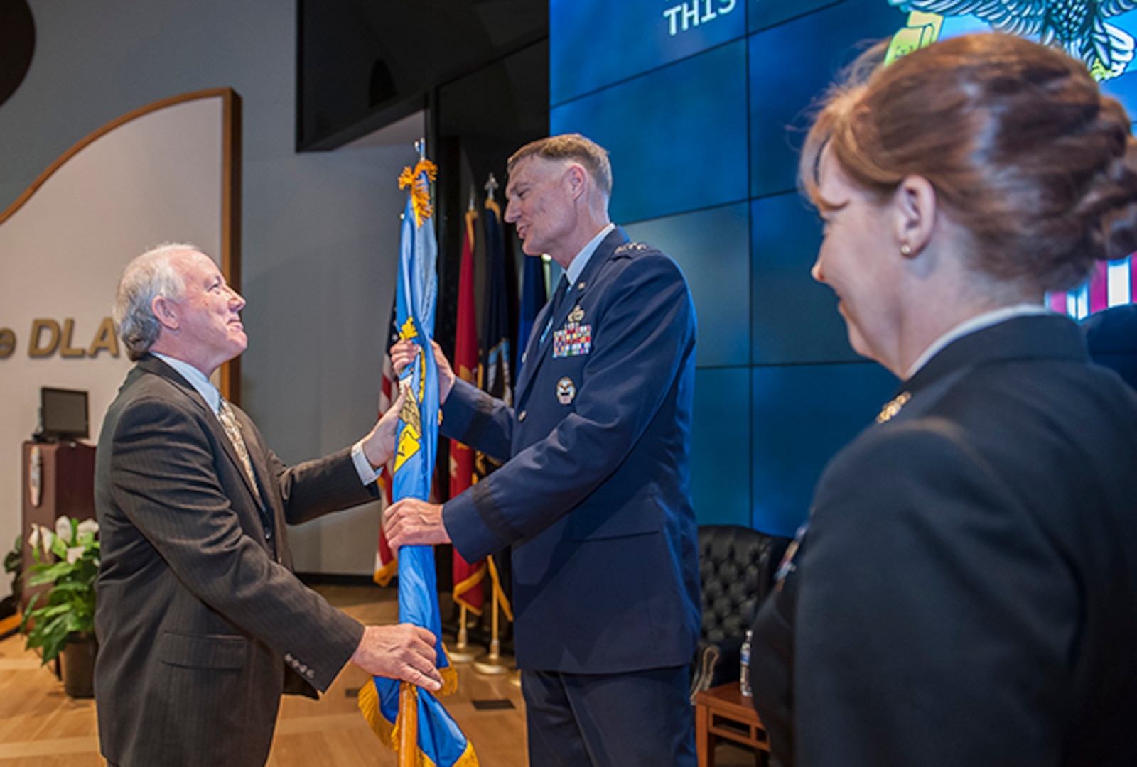 James McClaugherty passes the organization’s colors to Air Force Lt. Gen. Andy Busch, DLA director, during a change of command ceremony Oct. 31 in the DLA Land and Maritime Operations Center auditorium. McClaugherty transferred command to Navy Rear Adm. Michelle Skubic.