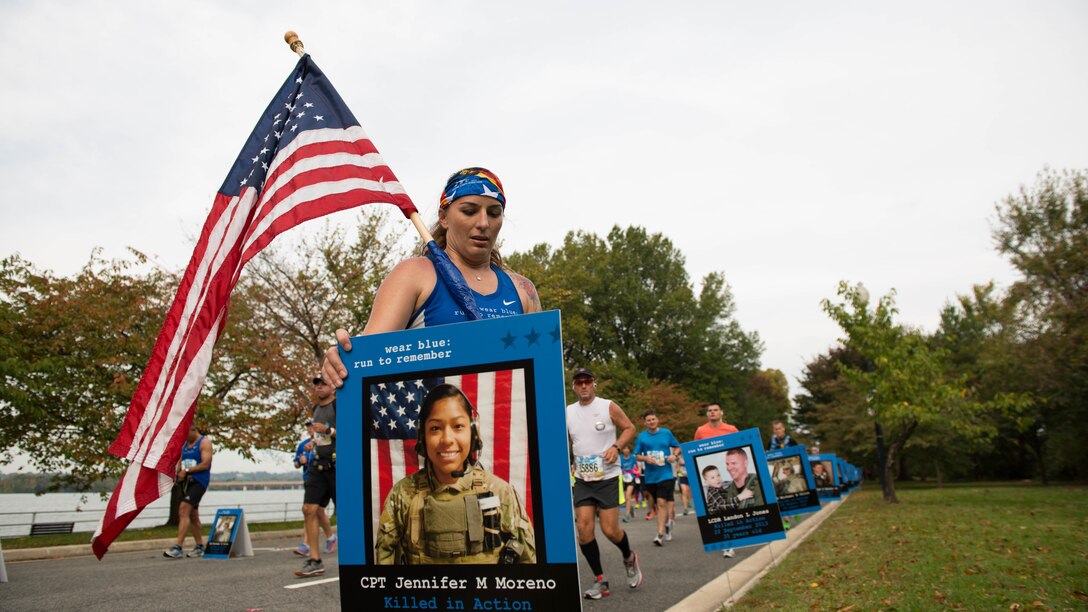 A runner pauses for a moment of reflection during the Marine Corps Marathon in Washington, D.C., Oct. 30, 2016. The posters were a part of the Wear Blue Mile, which honored fallen service members. Marine Corps photo by Lance Cpl. Timothy Smithers
