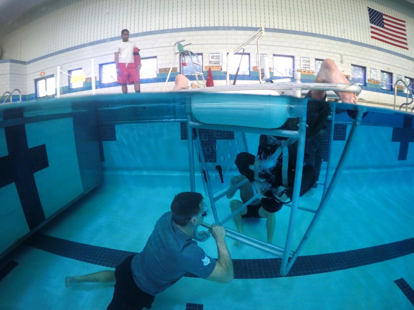 Maj. Jason Lott, 1st Helicopter Squadron pilot, sits upside down underwater during Helicopter Emergency Egress Device Training at Prince George’s Community College’s Robert I. Bickford Natatorium in Largo, Md., Oct. 28, 2016. The training, specific to helicopter aircrew, teaches the proper way to evacuate a helicopter if it goes down over a body of water. (U.S. Air Force photo by Senior Airman Philip Bryant)