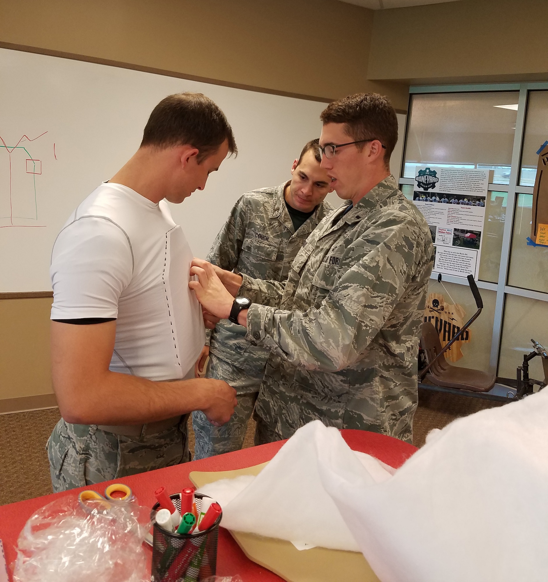 1st Lt. Jason Goins (right) and 2nd Lt. Mathew Couch fit the body armor prototype created in the AFRL Maker Hub to Capt. Lance Wilhelm, testing for wearability and body conformity.  (U.S. Air Force photo/Holly Jordan)