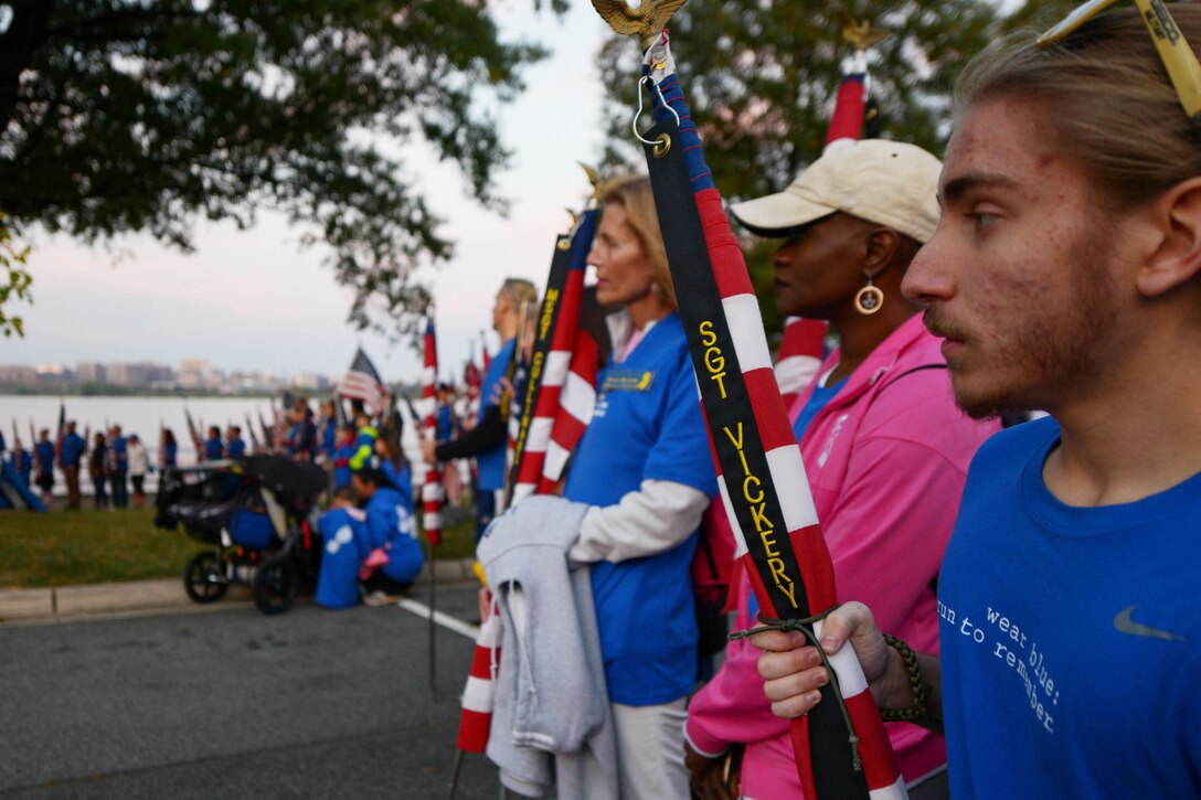 A volunteer, with Wear Blue: Run to Remember, stands with an American flag before the beginning of the Marine Corps Marathon in Washington, D.C., Oct. 30, 2016. Wear Blue is an organization that honors veterans who died in combat. Wear Blue participation at the marathon featured posters with pictures of fallen service members and members standing with American flags flanking both sides of the street. Marine Corps photo by Lance Cpl. Timothy R. Smithers