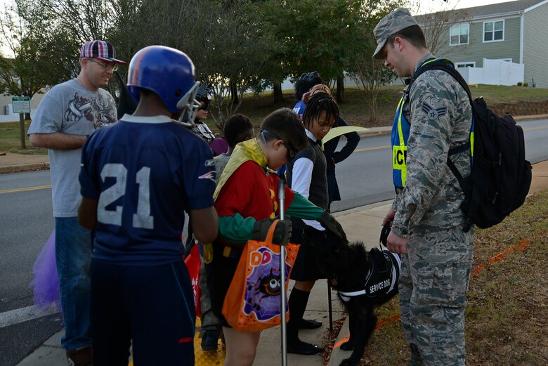 U.S. Air Force Senior Airman Jonathan Brown, 20th Maintenance Operations Squadron weapon systems coordinator, allows trick-or-treaters to pet his dog while volunteering at a Pumpkin Patrol event at Shaw Air Force Base, S.C., Oct. 31, 2016. Approximately 60 out of the 80 people protecting Team Shaw trick-or-treaters on Halloween night were volunteers serving as augmentees. (U.S. Air Force photo by Airman 1st Class BrieAnna Stillman)       