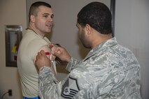 Master Sgt. Jason Fletcher, 166th Medical Group medical technician, places an adhesive bandage on the arm of Master Sgt. Jesse Hope, 736th Aircraft Maintenance Squadron home station check flight chief, after administering a flu vaccine Oct. 25, 2016, at the Landings on Dover Air Force Base, Del. Four Airmen from the 166th MDG assigned to the New Castle Air National Guard Base, Del., traveled to Dover AFB to assist the 436th MDG administer the flu vaccines. (U.S. Air Force photo by Senior Airman Aaron J. Jenne)