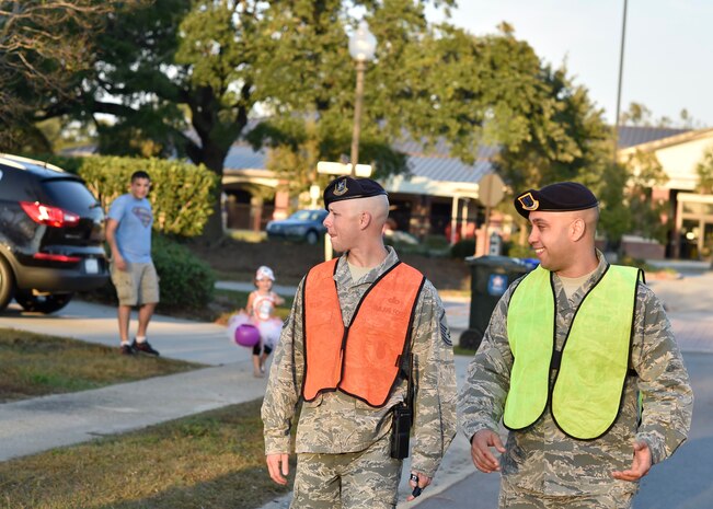 Master Sgt. John Miller, left, 628th Security Forces Squadron operations NCO in charge, and Capt. Chris Melendez Montanez, right, 628th SFS operations officer, keep an eye out for injured trick-or-treaters while on Pumpkin Patrol here, Oct. 31, 2016. On Halloween, members of Joint Base Charleston volunteered for Pumpkin Patrol to walk through base housing on the lookout for injured or lost children.