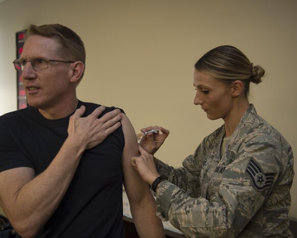 U.S. Navy Capt. Robert Hudson, left, Joint Base Charleston deputy commander, receives his annual flu shot from Staff Sgt. Sarah Woods, right, 628th Medical Group (MDG) NCO in charge of the allergy and immunizations clinic, Oct. 21. The 628th MDG began offering the flu shot to active-duty service members, children from ages three to 17 and high-risk adults Oct. 17. Beginning Nov. 1, the influenza vaccine is available to all DoD beneficiaries. Additionally, the Air Base Exchange will offer a flu line on Nov. 19 from 1000 to 1300. 