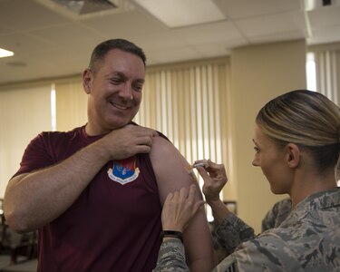 U.S. Air Force Col. Robert Lyman, left, Joint Base Charleston commander, receives his annual flu shot from Staff Sgt. Sarah Woods, right, 628th Medical Group (MDG) NCO in charge of the allergy and immunizations clinic, Oct. 21. The 628th MDG began offering the flu shot to active-duty service members, children from ages three to 17 and high-risk adults Oct. 17. Beginning Nov. 1, the influenza vaccine is available to all DoD beneficiaries. Additionally, the Air Base Exchange will offer a flu line on Nov. 19 from 1000 to 1300. 