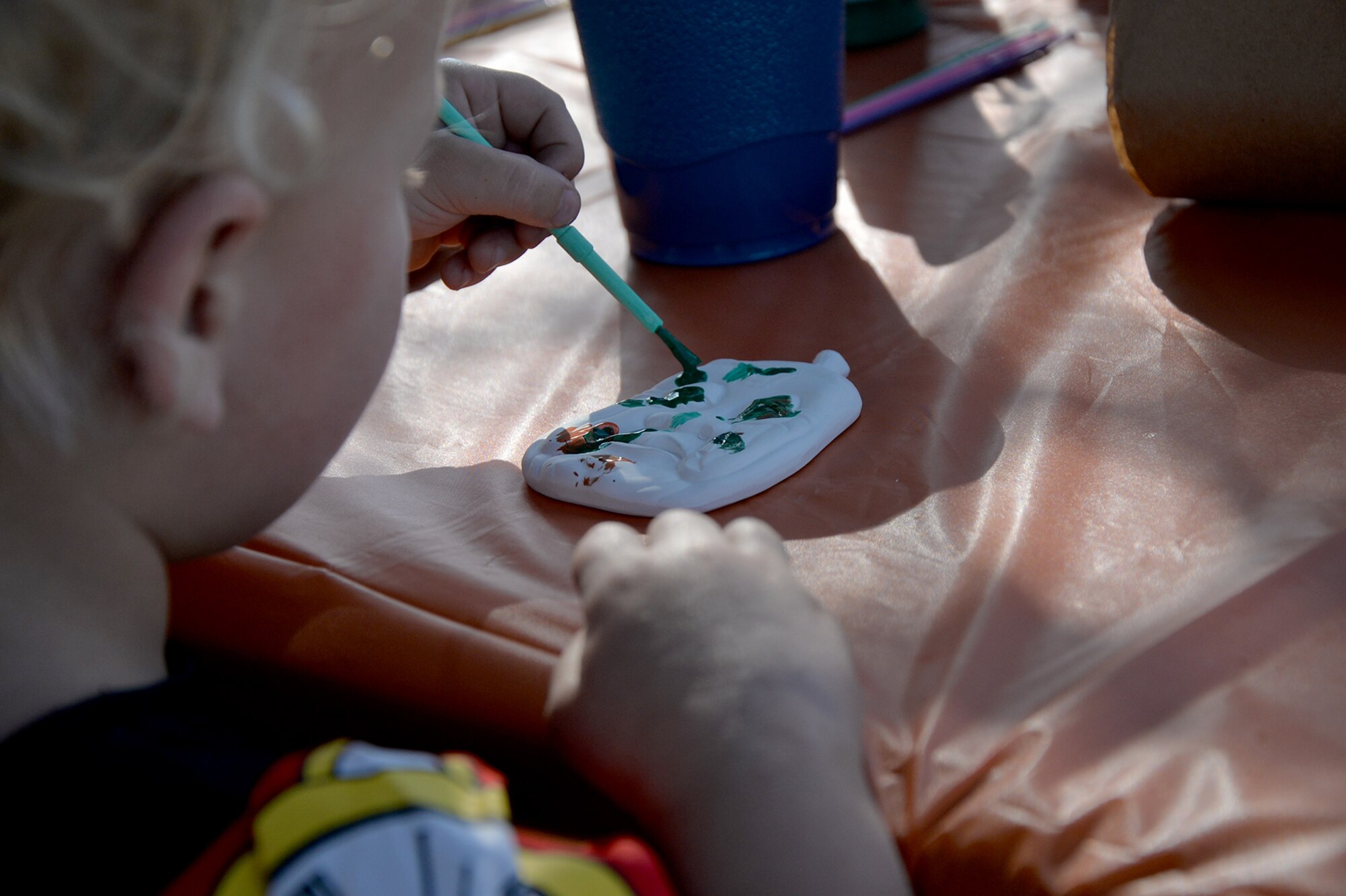 A child paints a ceramic pumpkin outside the base theater during Ghoulfellow on Goodfellow Air Force Base, Texas, Oct. 28, 2016. Families could dress up and enjoy Trunk or Treat, carnival games and a hay ride.  (U.S. Air Force photo by Airman 1st Class Randall Moose/Released)